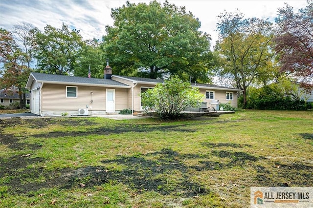 rear view of property featuring a garage and a lawn