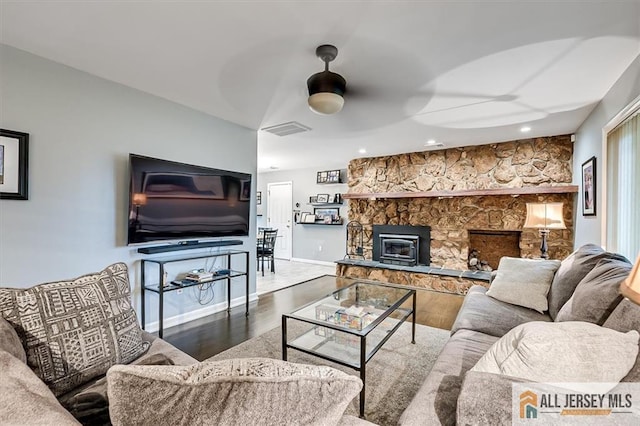 living room with hardwood / wood-style flooring and a stone fireplace