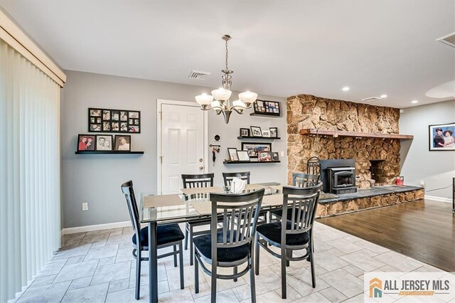 dining space with an inviting chandelier and a wood stove