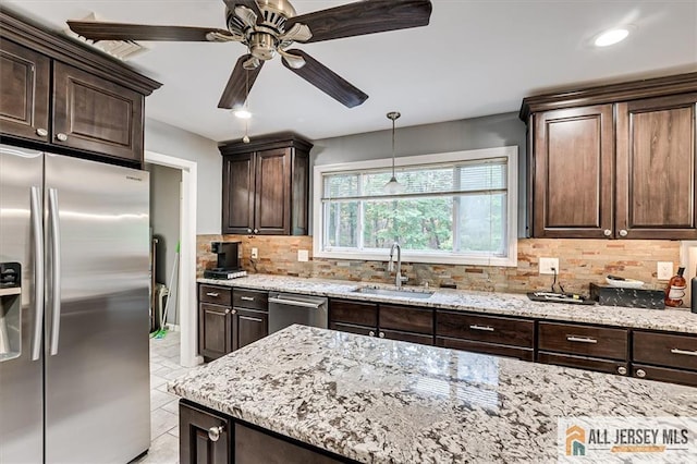 kitchen featuring appliances with stainless steel finishes, tasteful backsplash, sink, hanging light fixtures, and dark brown cabinets