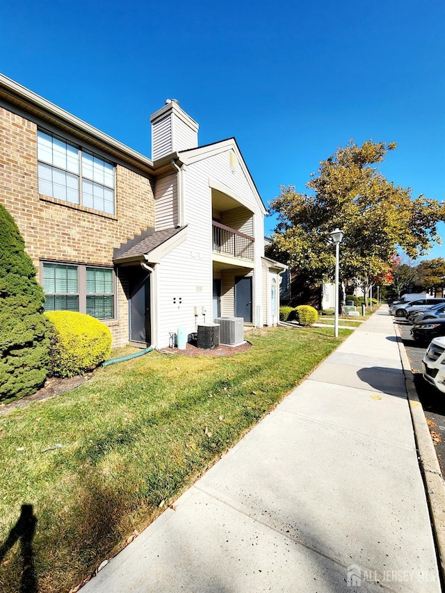 view of side of home featuring central air condition unit and a yard