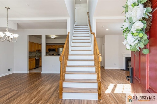 199 Pinelli Dr, Piscataway, NJ 08854 - stairs with wood finished floors, a chandelier, and a fireplace with flush hearth