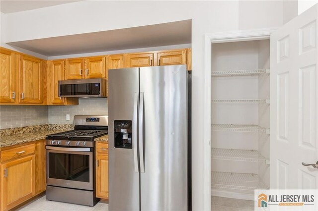 199 Pinelli Dr, Piscataway, NJ 08854 - kitchen featuring appliances with stainless steel finishes, light stone counters, decorative backsplash, and light tile patterned flooring