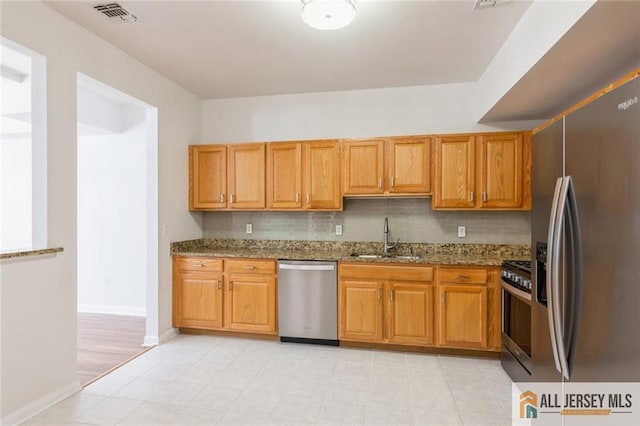 199 Pinelli Dr, Piscataway, NJ 08854 - kitchen featuring appliances with stainless steel finishes, dark stone counters, decorative backsplash, light tile patterned floors, and brown cabinets
