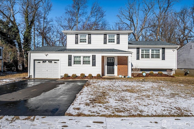 tri-level home featuring a garage and aphalt driveway