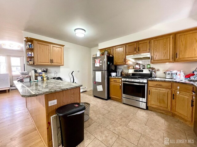 kitchen with kitchen peninsula, appliances with stainless steel finishes, tasteful backsplash, dark stone counters, and a baseboard radiator