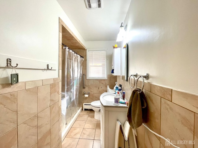 bathroom featuring tile patterned floors, toilet, tile walls, vanity, and a baseboard heating unit