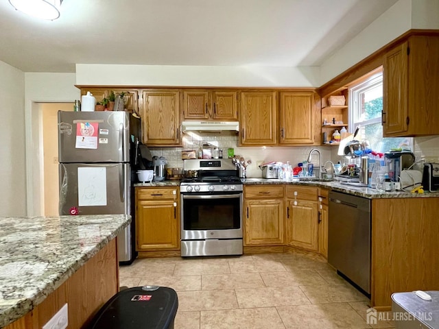 kitchen with sink, stainless steel appliances, light stone counters, decorative backsplash, and light tile patterned flooring