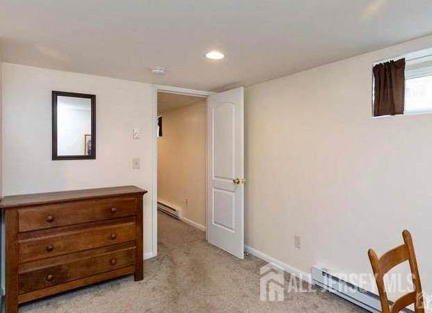 bedroom with light colored carpet and baseboard heating