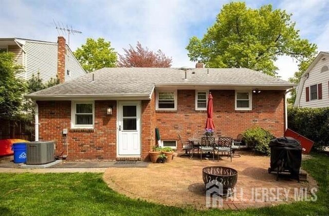 rear view of house featuring a fire pit, central AC unit, a patio area, and a lawn