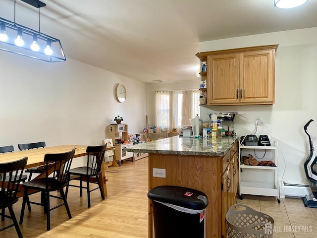 kitchen with baseboard heating, kitchen peninsula, hanging light fixtures, and light hardwood / wood-style flooring