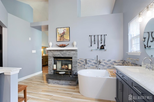 22 Fairway Blvd, Monroe, NJ 08831 - bathroom featuring vanity, a freestanding bath, a stone fireplace, vaulted ceiling, and wood finished floors