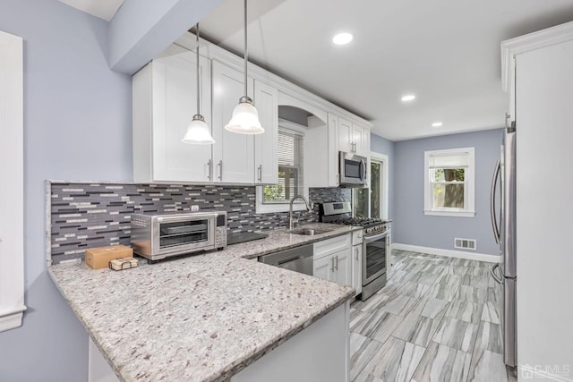 261 New Market Rd, Dunellen, NJ 08812 - kitchen featuring stainless steel appliances, a peninsula, white cabinets, tasteful backsplash, and light stone counters