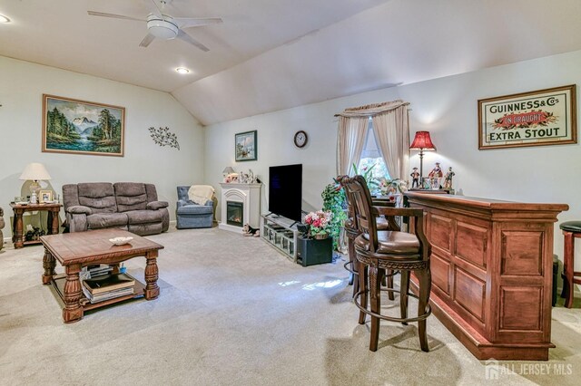 815 Marlboro Rd, Old Bridge, NJ 08857 - living room with carpet floors, vaulted ceiling, ceiling fan, a dry bar, and a lit fireplace