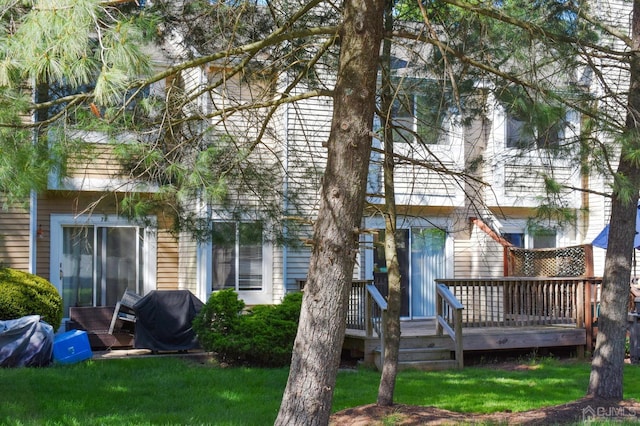 back of property with a yard and a wooden deck