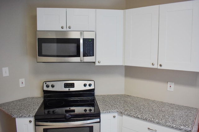 kitchen with light stone countertops, white cabinets, and stainless steel appliances