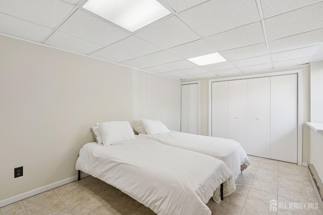 bedroom featuring a paneled ceiling, light tile patterned flooring, and baseboards