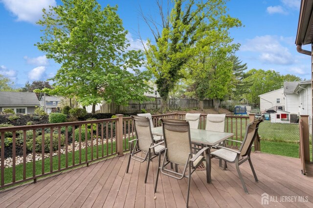 wooden deck with a fenced backyard and outdoor dining space