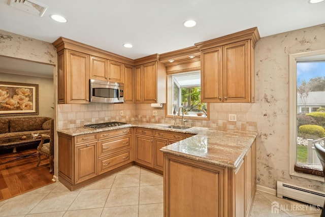 kitchen featuring a baseboard heating unit, light stone counters, visible vents, a sink, and appliances with stainless steel finishes