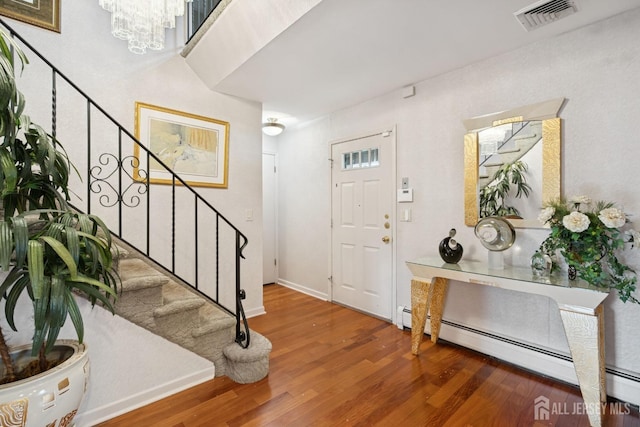 entrance foyer featuring a baseboard radiator, stairs, visible vents, and wood finished floors
