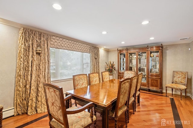 dining room with crown molding, light wood-type flooring, visible vents, and a baseboard heating unit