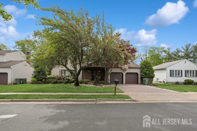 view of property hidden behind natural elements with driveway, a front yard, and an attached garage