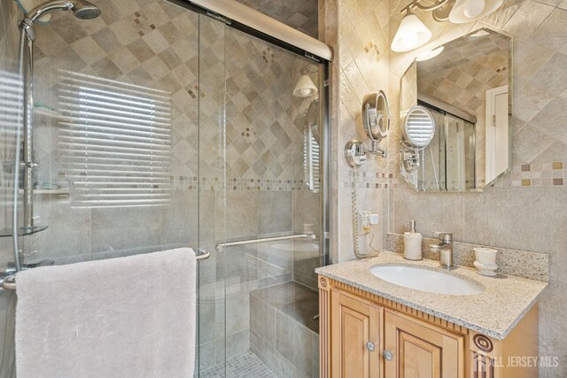 full bathroom with tile walls, vanity, and a stall shower