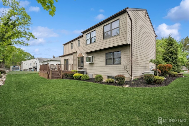 back of house featuring a lawn and a deck