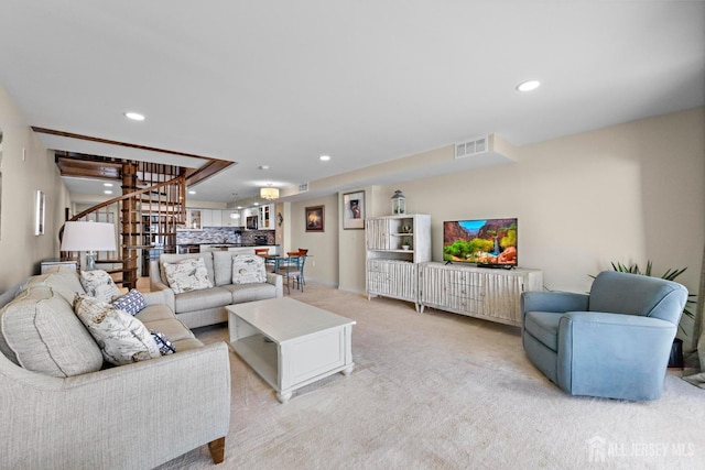 living area with light carpet, visible vents, recessed lighting, and stairs