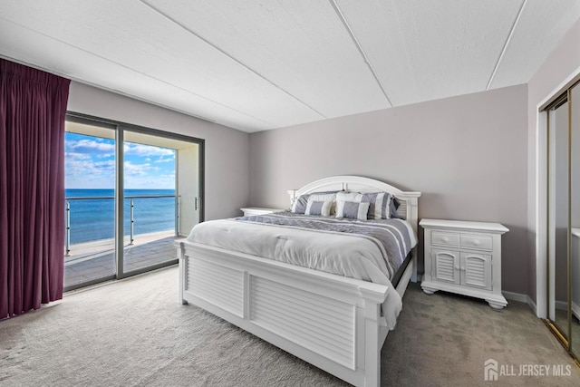 bedroom with a water view, access to outside, a textured ceiling, carpet, and baseboards