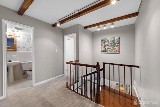 hallway with beamed ceiling, an upstairs landing, visible vents, carpet, and tile walls