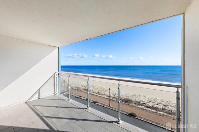 balcony featuring a view of the beach and a water view