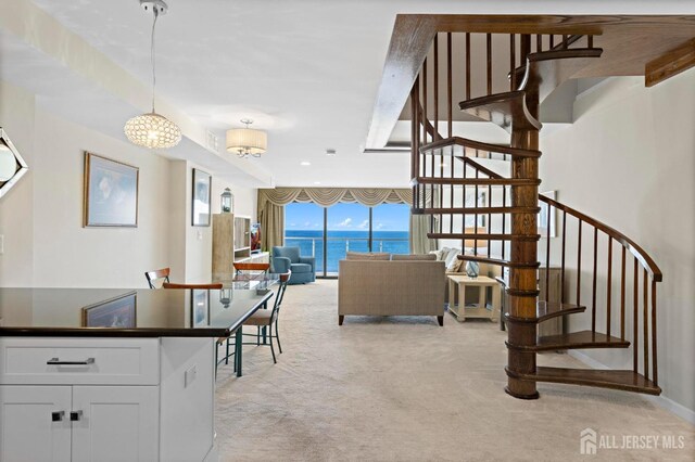 interior space featuring stairway, light colored carpet, and a wall of windows