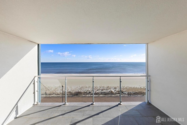 balcony featuring a water view and a beach view