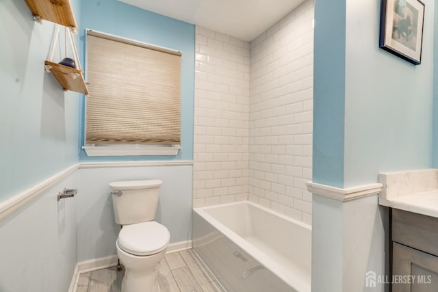 full bathroom featuring vanity, tiled shower / bath combo, and toilet