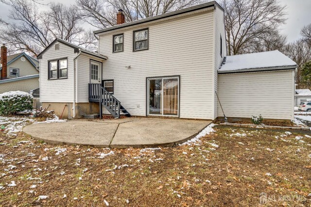 snow covered back of property featuring a patio area