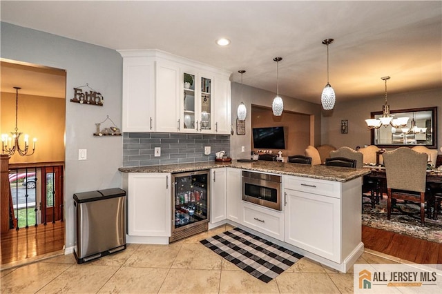 kitchen with wine cooler, white cabinetry, and a chandelier