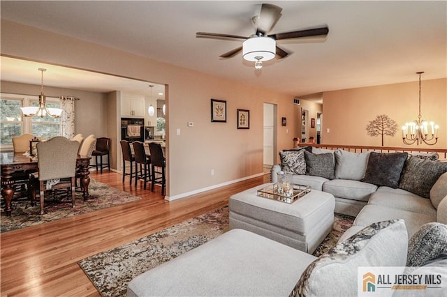 living room with hardwood / wood-style floors and ceiling fan with notable chandelier