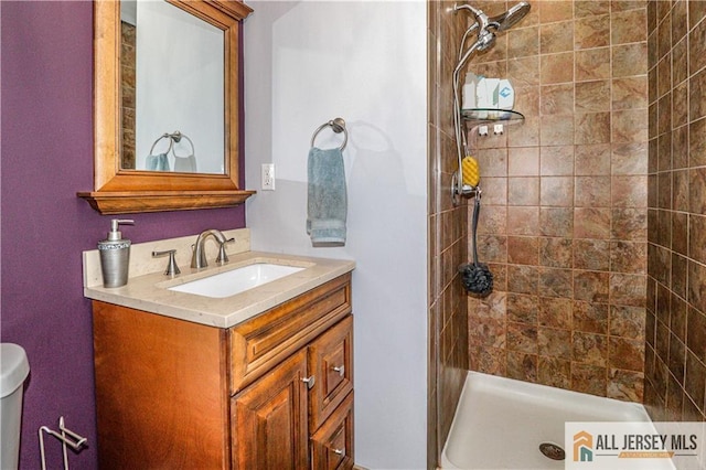 bathroom featuring vanity, a tile shower, and toilet