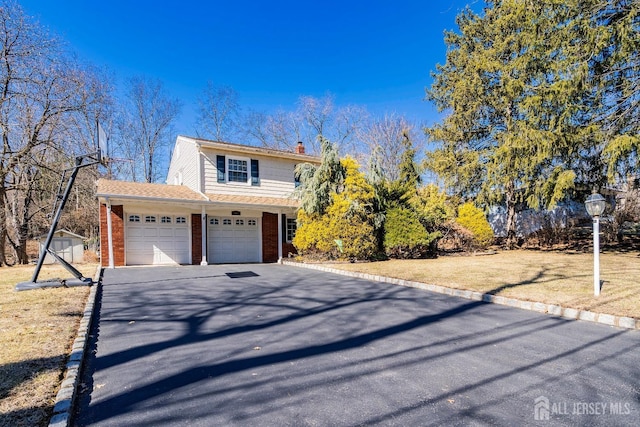 view of front of house featuring a garage, driveway, brick siding, and a chimney