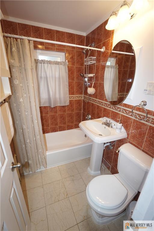 25 Clover Ave, Colonia, NJ 07067 - bathroom with tile walls, shower / tub combo, toilet, and ornamental molding
