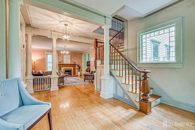 44 Rector St, Metuchen, NJ 08840 - stairway featuring crown molding, hardwood / wood-style floors, a fireplace, and ornate columns