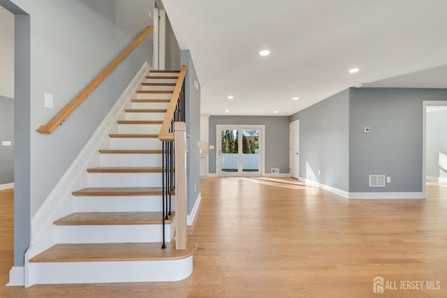 staircase with visible vents, baseboards, wood finished floors, and recessed lighting