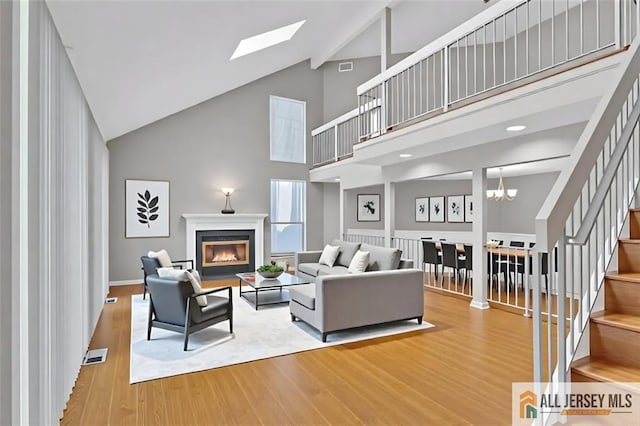 22 Witch Hazel Ct, South Brunswick, NJ 08852 - living area with high vaulted ceiling, stairway, a glass covered fireplace, wood finished floors, and a skylight