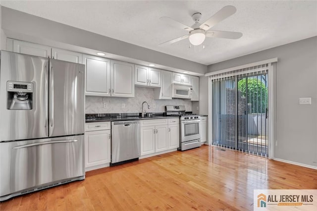 22 Witch Hazel Ct, South Brunswick, NJ 08852 - kitchen with stainless steel appliances, dark countertops, light wood-type flooring, a ceiling fan, and decorative backsplash
