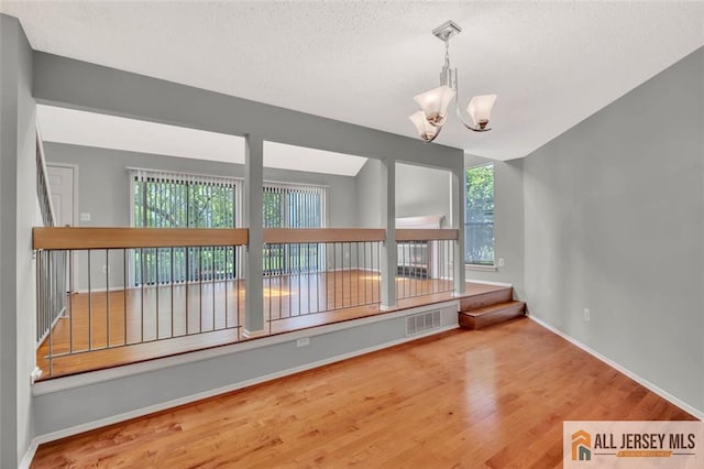 22 Witch Hazel Ct, South Brunswick, NJ 08852 - spare room featuring wood finished floors, a textured ceiling, and a chandelier