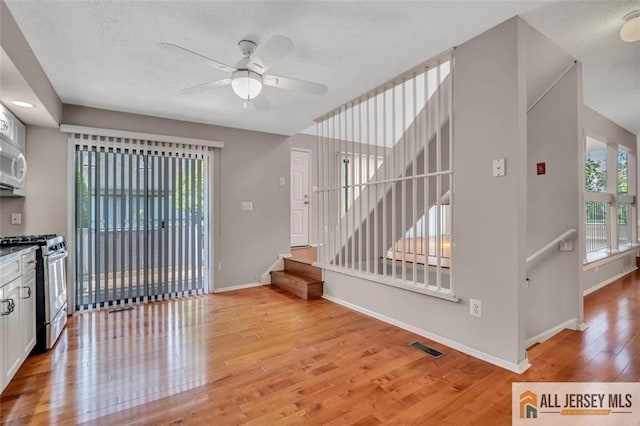 22 Witch Hazel Ct, South Brunswick, NJ 08852 - kitchen with stainless steel range with gas stovetop, light wood finished floors, ceiling fan, a textured ceiling, and white cabinetry