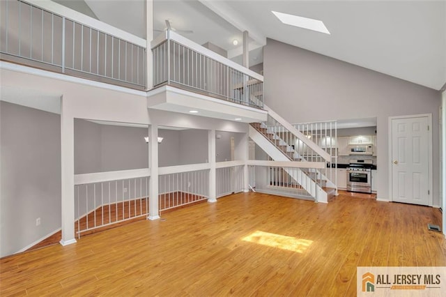 22 Witch Hazel Ct, South Brunswick, NJ 08852 - unfurnished living room featuring stairway, high vaulted ceiling, a skylight, and light wood-style floors