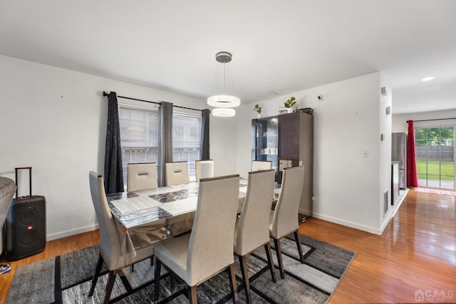 dining space featuring baseboards, wood finished floors, and an inviting chandelier