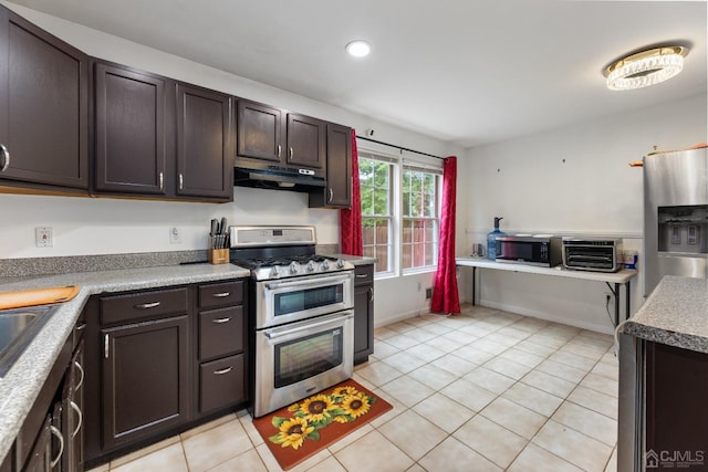 kitchen featuring a toaster, stainless steel appliances, dark brown cabinets, under cabinet range hood, and light tile patterned flooring